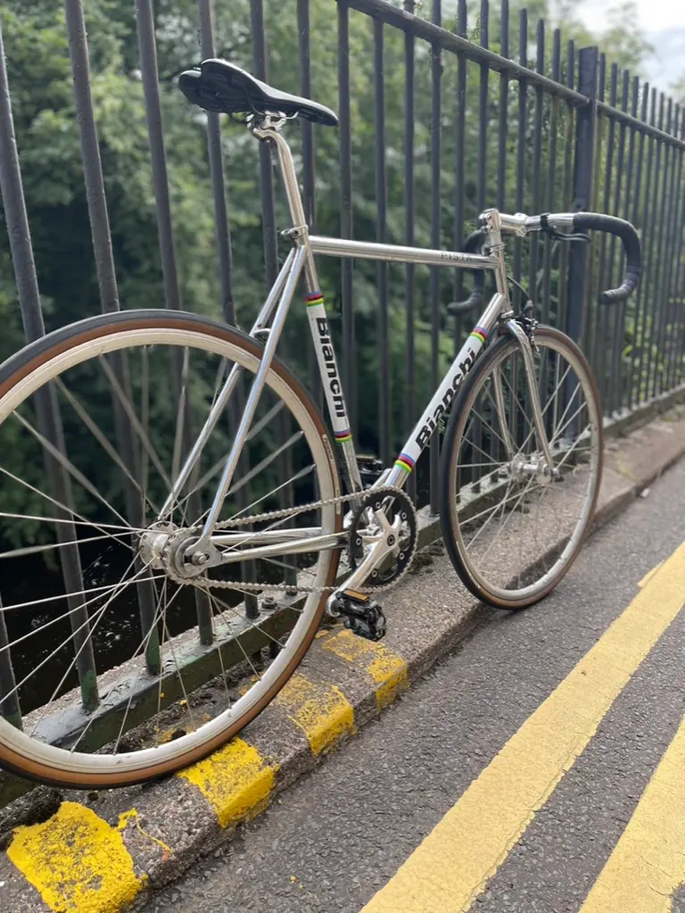 A silver fixed-gear bike leaning on black railings