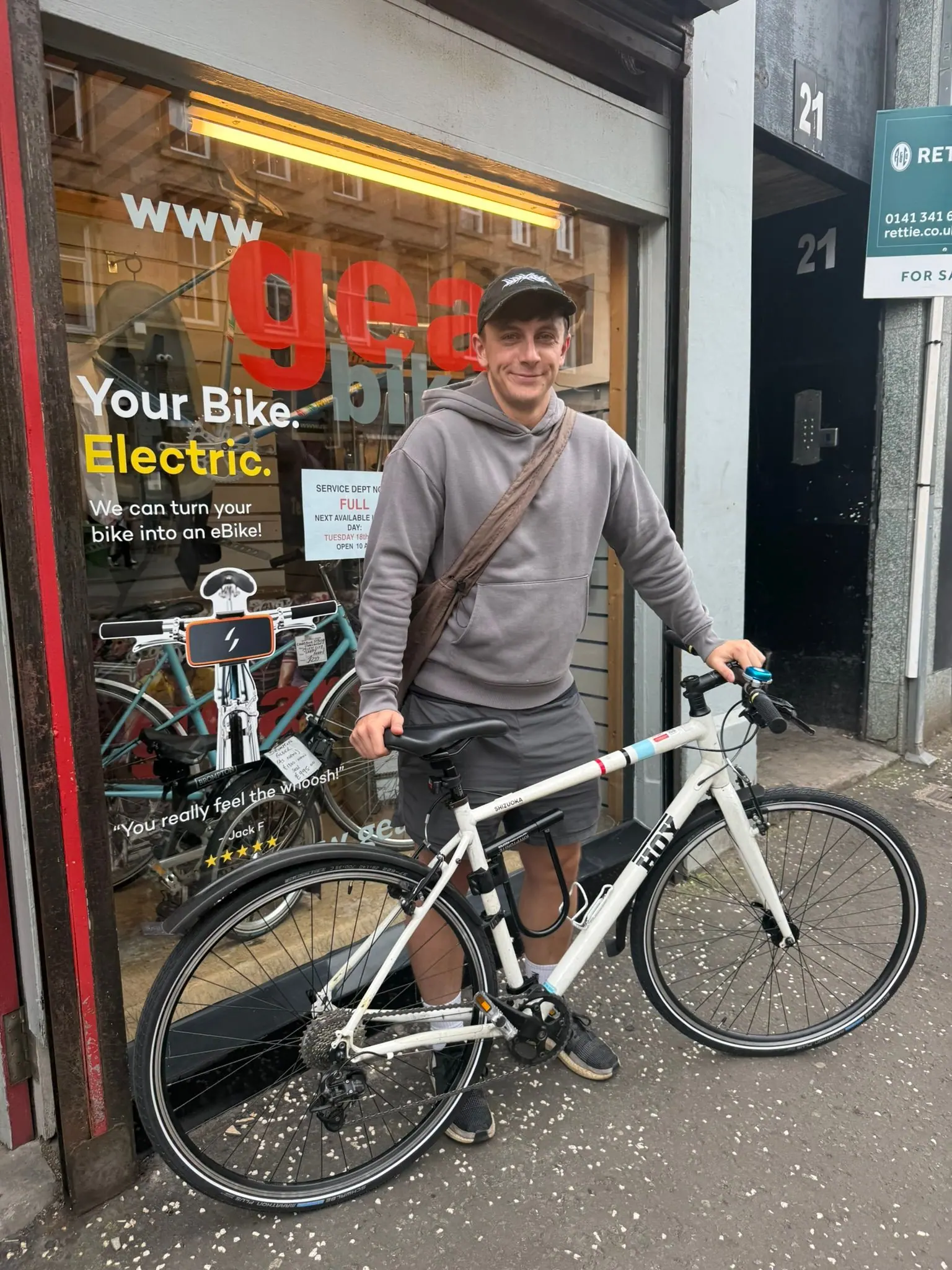 A customer with a white road bike outside the Gear Bikes shopfront
