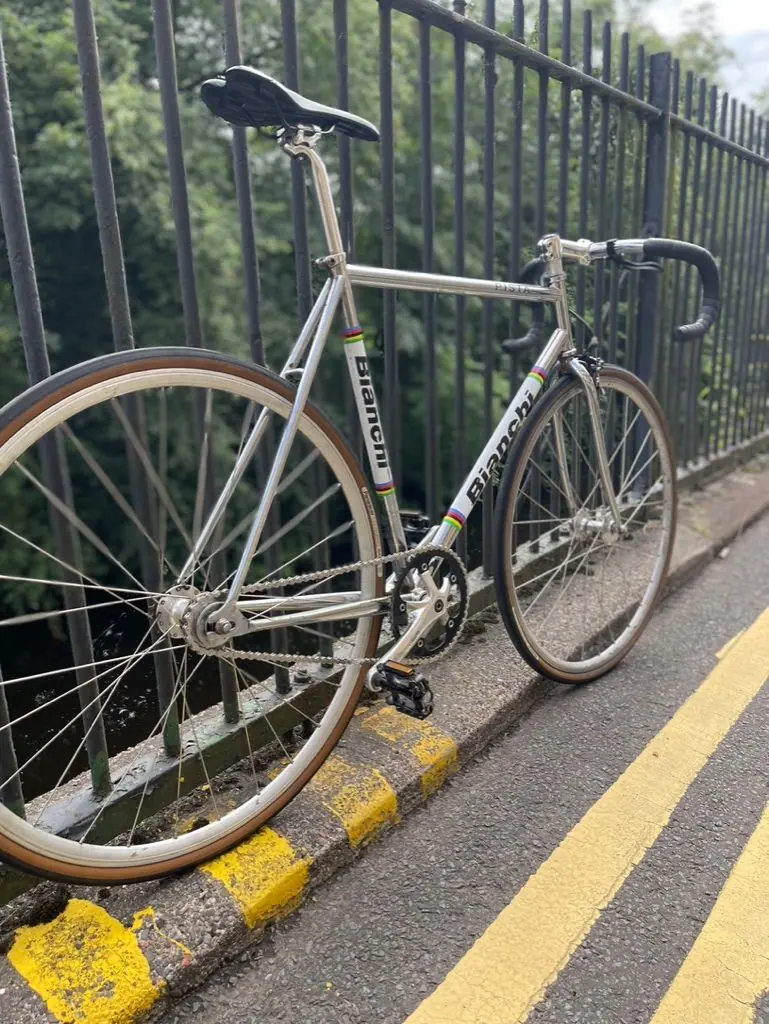 A silver fixed-gear bike leaning on black railings