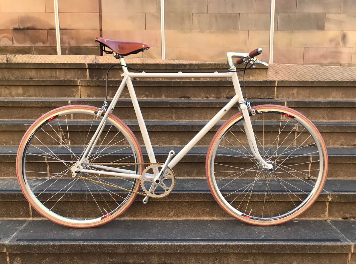 A cream single-speed bike with tan-wall tyres