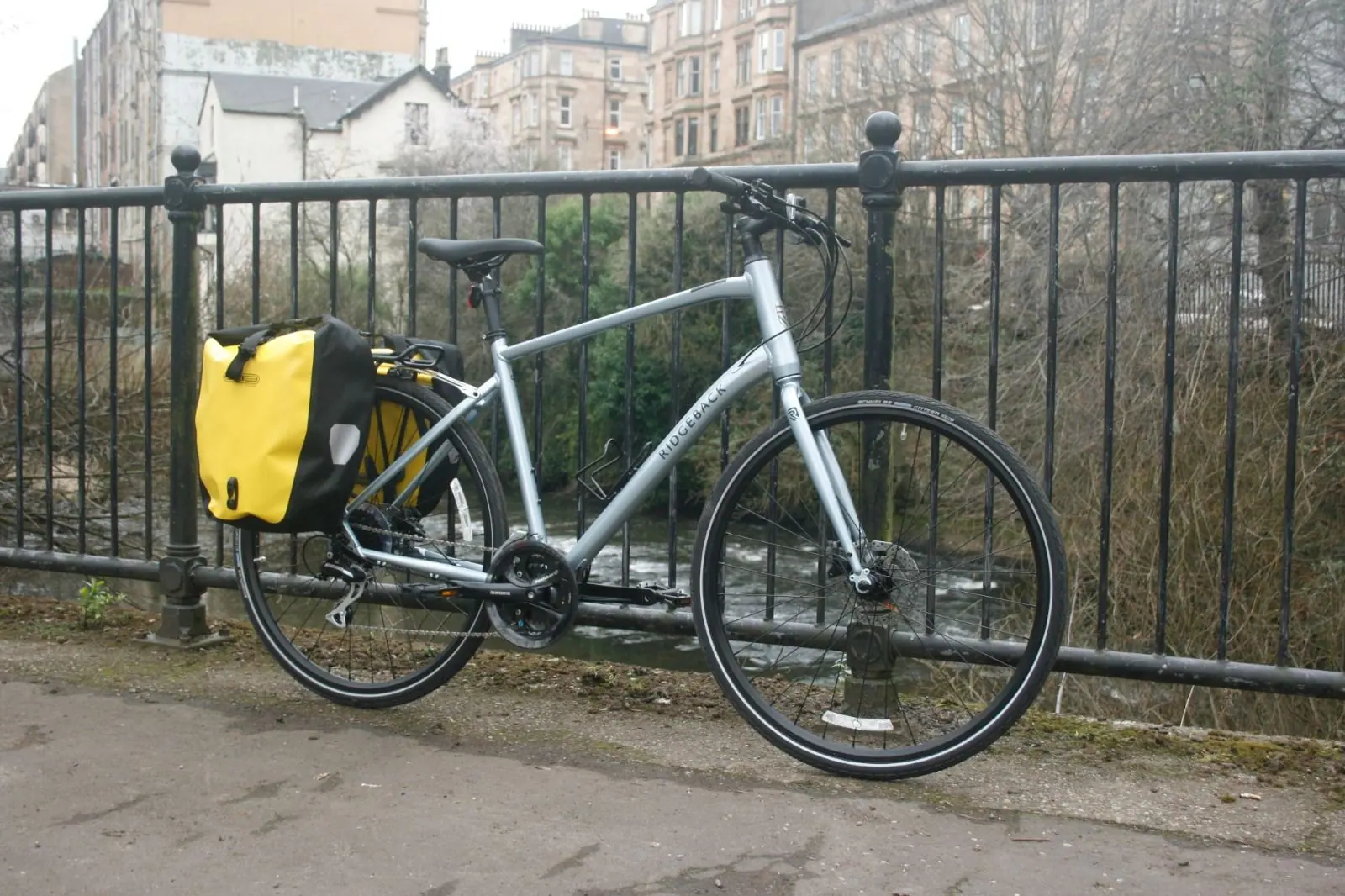 A hire bike with a yellow Ortlieb pannier against iron railings in the West End